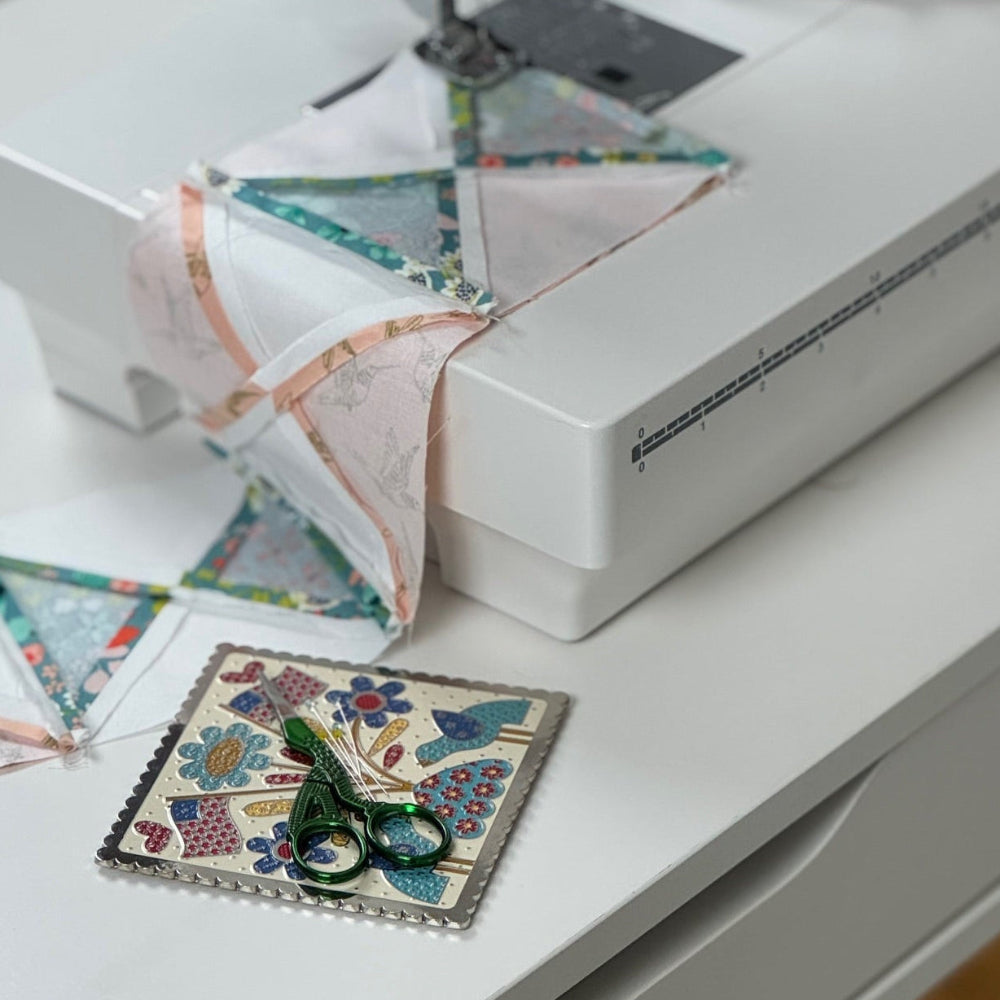 Sewing machine with fabric pieces on a white surface