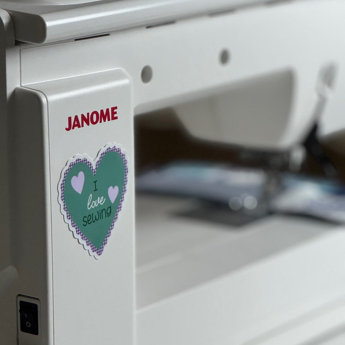 A Janome sewing machine with a heart-shaped sticker that says I Love Sewing.