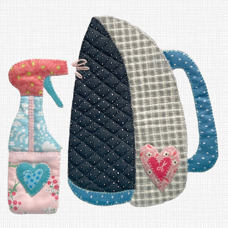 A handmade quilted applique iron and spray bottle set on a white grid background. The iron has a navy blue polka dot section, a gray and white gingham section, and a blue handle with a pink heart applique.