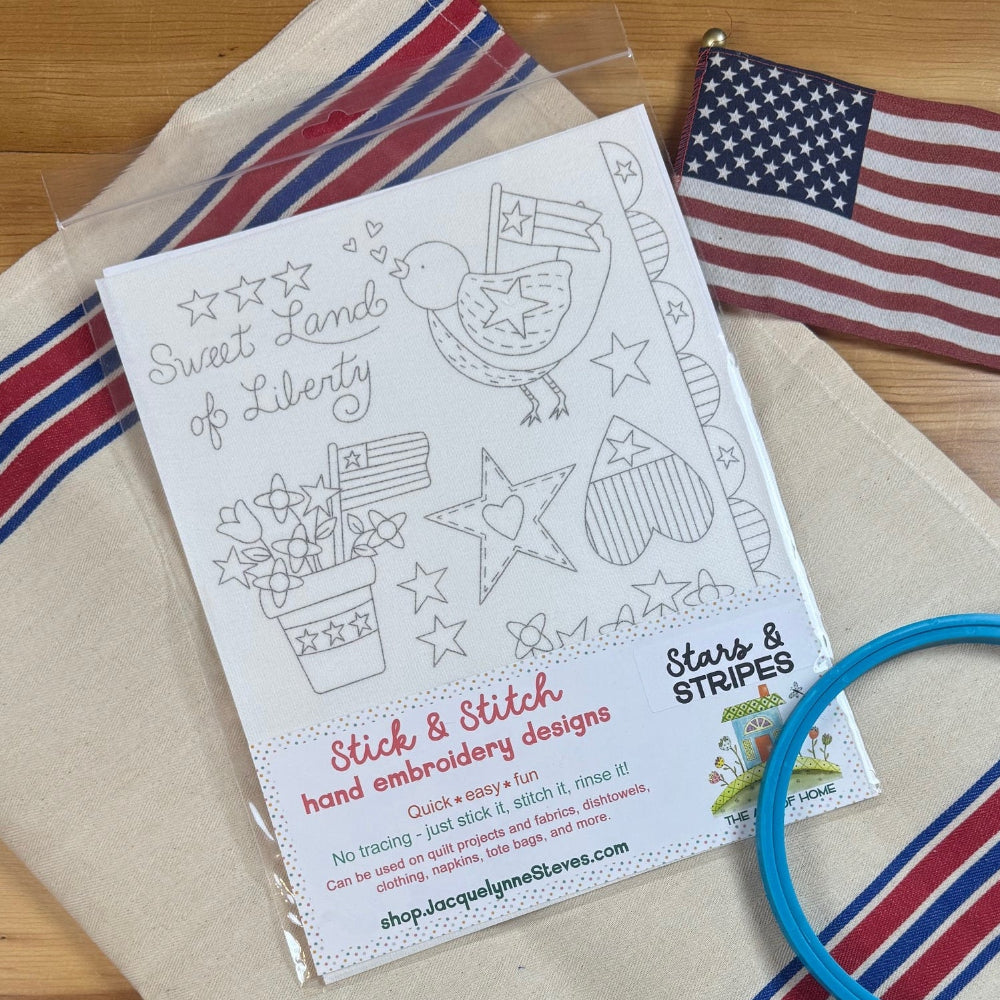 Patriotic design sheet on red and blue striped towel and American flag.