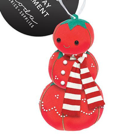 Red tomato-shaped ornament with a white label on a white background