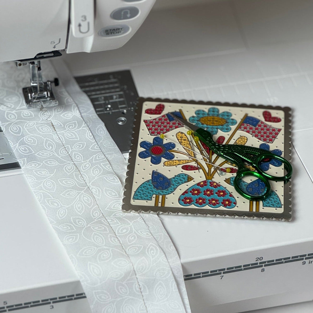 Sewing machine with a small quilted square on the presser foot
