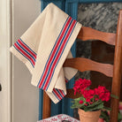 Red and blue striped tea towels hanging on wooden chair.