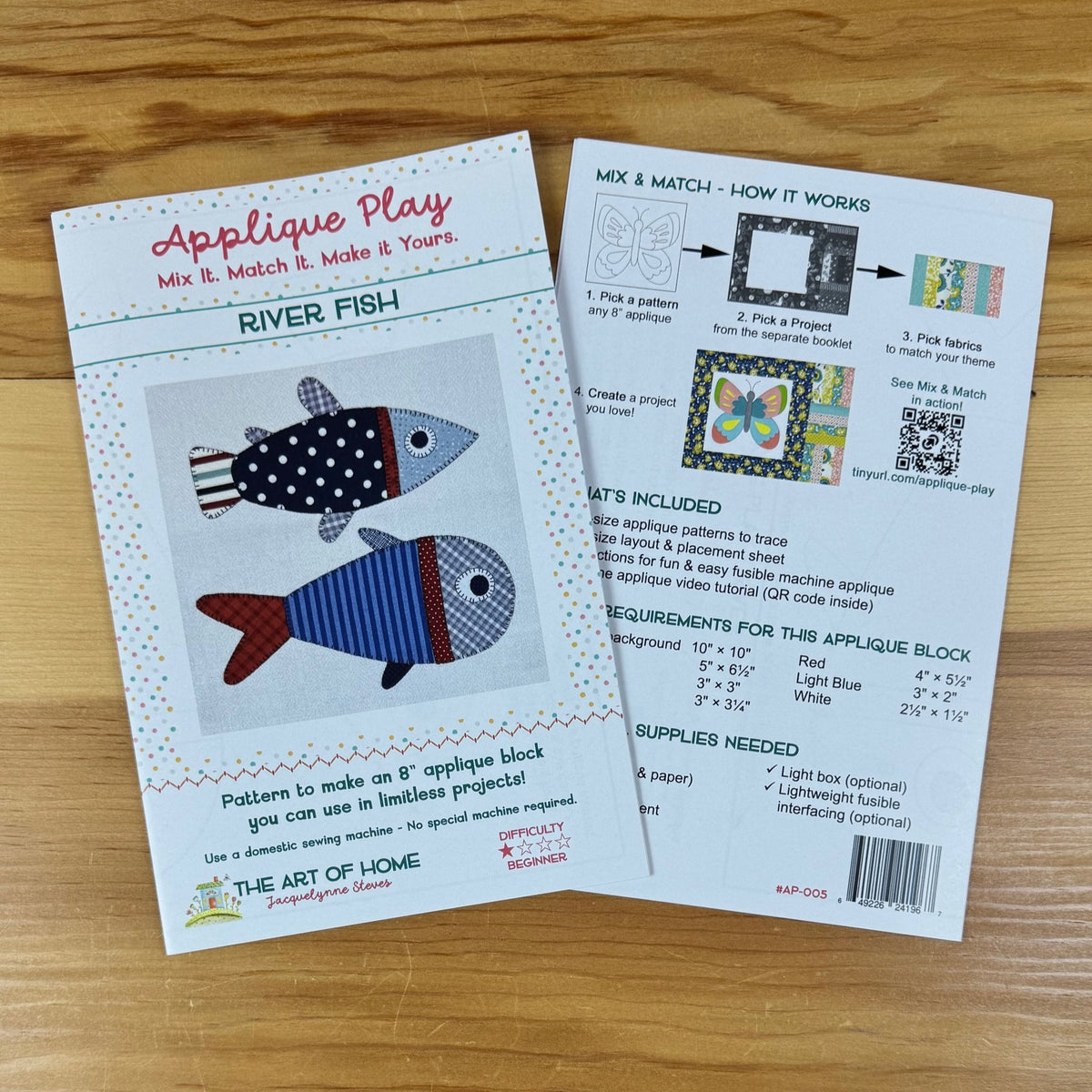 Two printed pattern sheets for an applique block titled "Applique Play" and "River Fish" laid on a light wood surface. The front sheet shows colorful fish designs with text including "Mix It.