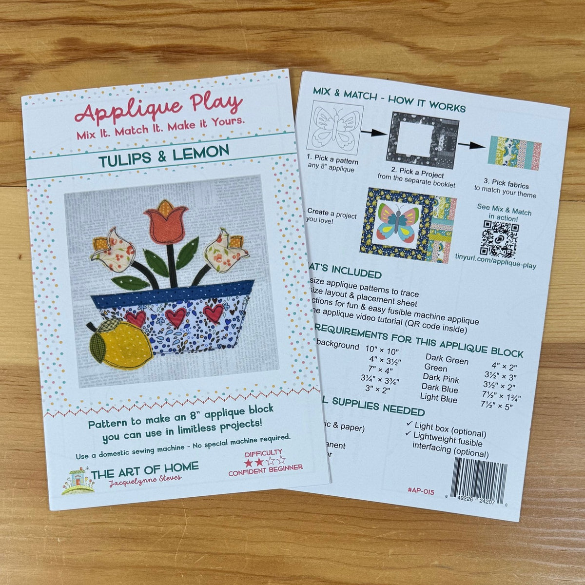 Front and back covers for an applique block pattern titled 'Tulips & Lemon' by The Art of Home, shown on a light wood surface. The front card shows a colorful floral design and instructions, while the back card includes a 'Mix & Match - How It Works' diagram and included supplies list.