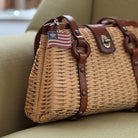 Wicker handbag with leather straps on a beige surface