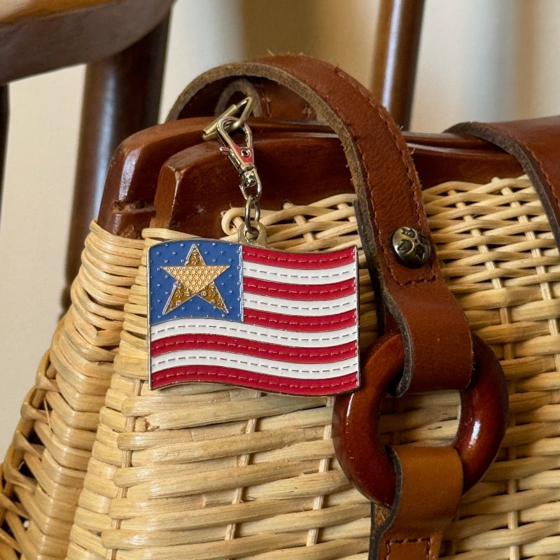 Enamel flag charm hanging on wicker and leather pocketbook