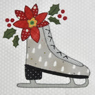 A festive applique or design of a light gray ice skate decorated with white pine trees, a red poinsettia flower, green holly leaves, and red berries on a white patterned fabric background.