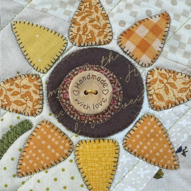 Quilt block with a floral design featuring various shapes and colors.