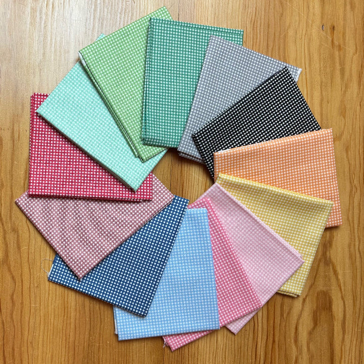 Color swatches arranged in a circular pattern on a wooden surface with a person sitting on a rug.