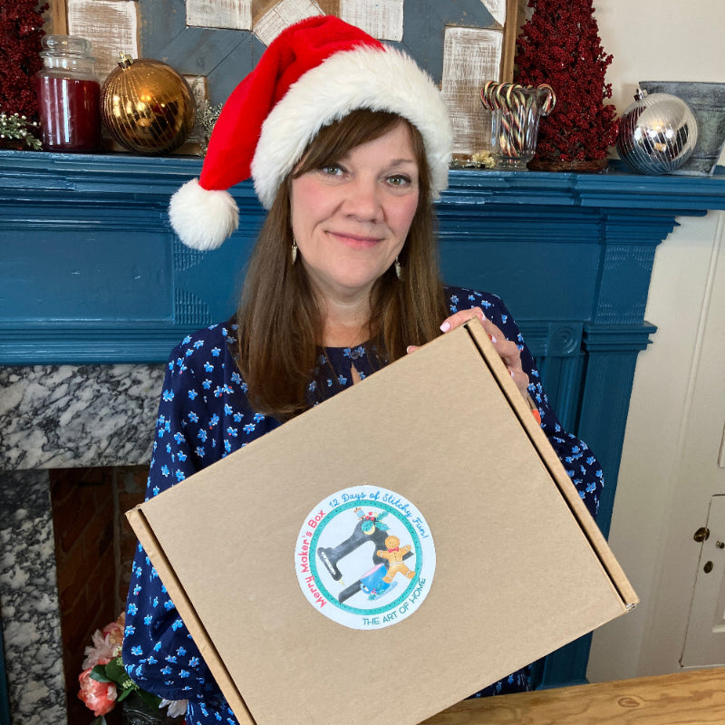 Jacquelynne Steves holding brown box with fireplace in background.