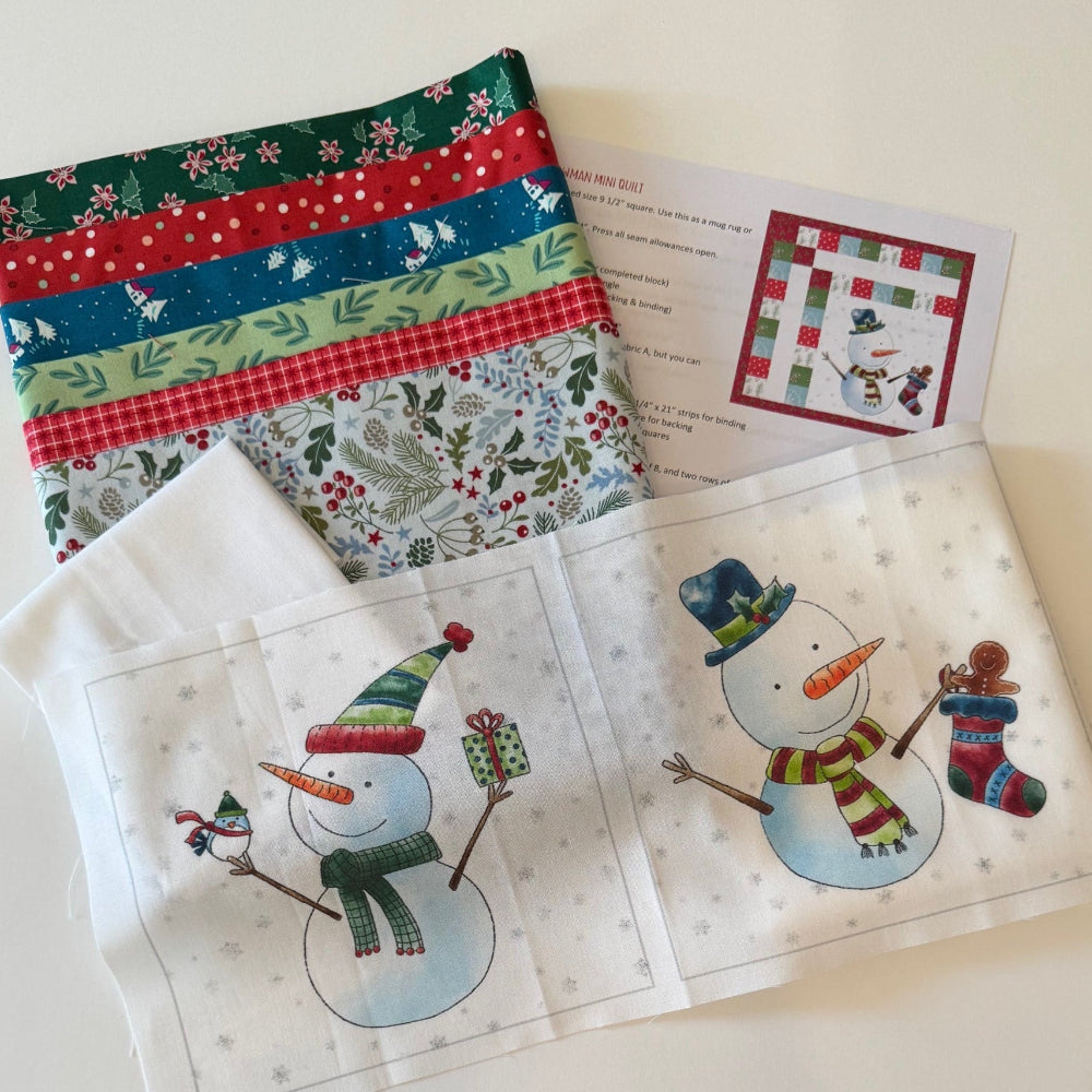 Quilt blocks with snowmen and Christmas-themed fabric on a table.