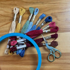 Embroidery hoop with colorful threads and scissors on a wooden table
