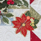 Poinsettia needle minder with pins on Christmas quilt