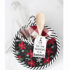 Decorative pot holder with floral pattern, wooden spoon, whisk, and 'Tis the Season to be Baking tag on a white background.