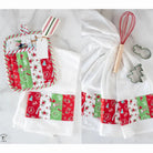 Set of Christmas-themed kitchen towels with a whisk and cookie cutters on a white background