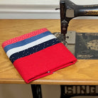 Red fabric with blue and white stripes on a sewing machine