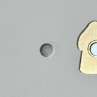 Round replacement magnet for needle minders next to the back of a gold needle minder.