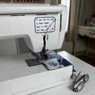 A sewing machine with a seam ripper on a small blue and white quilt and a sticker that says "If you see with a seam ripper, now is not the time."