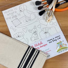 Embroidery kit with hoop, threads, pattern paper, and fabric on a wooden surface.