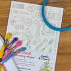 Embroidery hoop and floss on stick & stitch sewing-themed embroidery sheet.