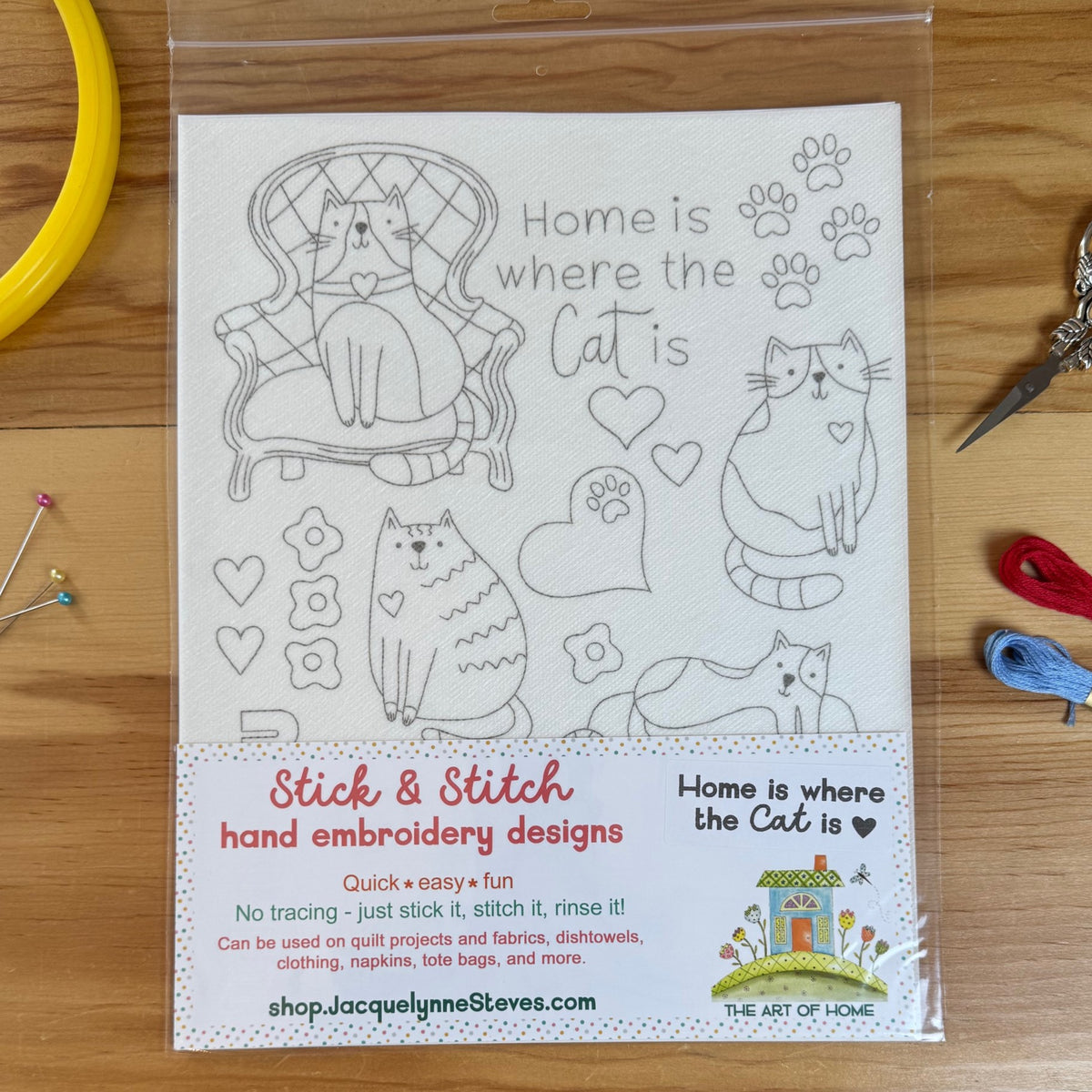 Stick & Stitch embroidery sheet with various cat designs on wood table surrounded by sewing notions.