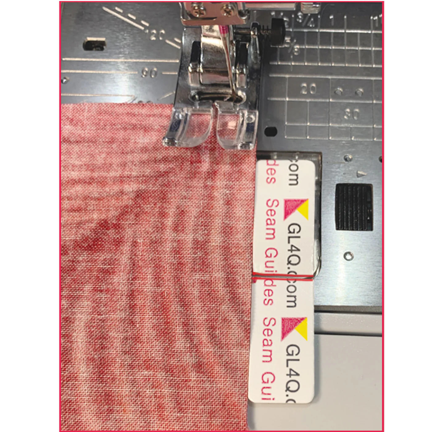 Sewing machine with a red fabric and a clear ruler attached, on a white background