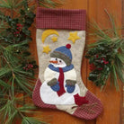 Christmas stocking with a snowman design hanging on a wooden door with greenery.