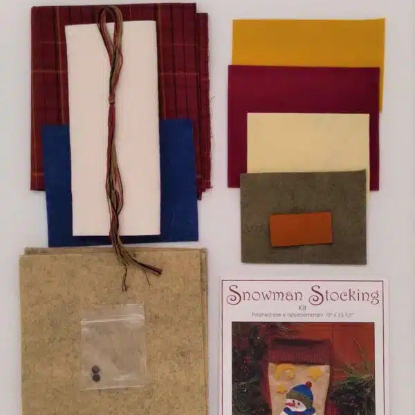 Crafting materials and a pattern book for making a snowman stocking on a white background.