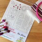 Stick & Stitch Valentine theme with embroidery hoop, fabric, and thread on a wooden table with a colorful rug in the background.