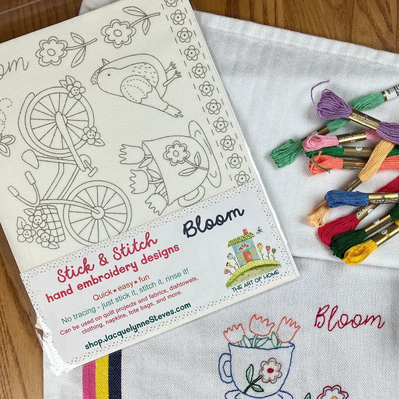 Stick & Stitch Floral theme with birds & bicycle pictured with thread, and embroidered towel on a wooden surface