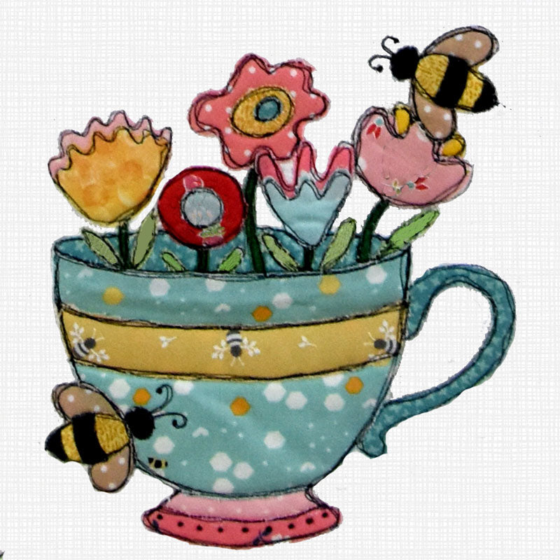A whimsical applique design of a teal teacup filled with colorful flowers and decorated with bumblebees, set against a white textured fabric background.
